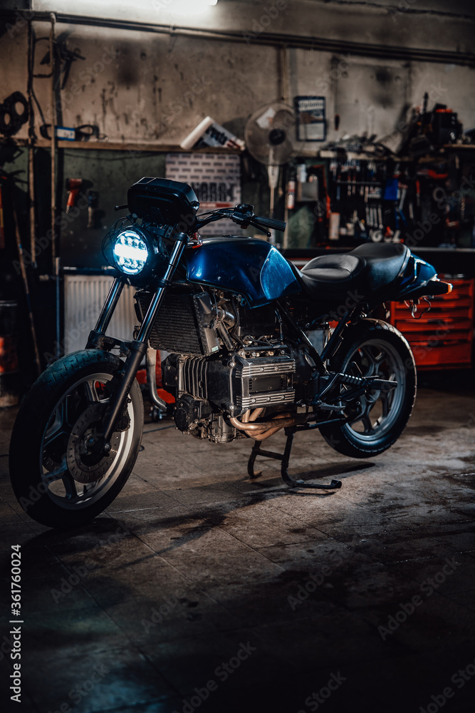 Custom bobber motorcycle with front light on in workshop or garage Custom bobber motorcycle with front light on in workshop or garage