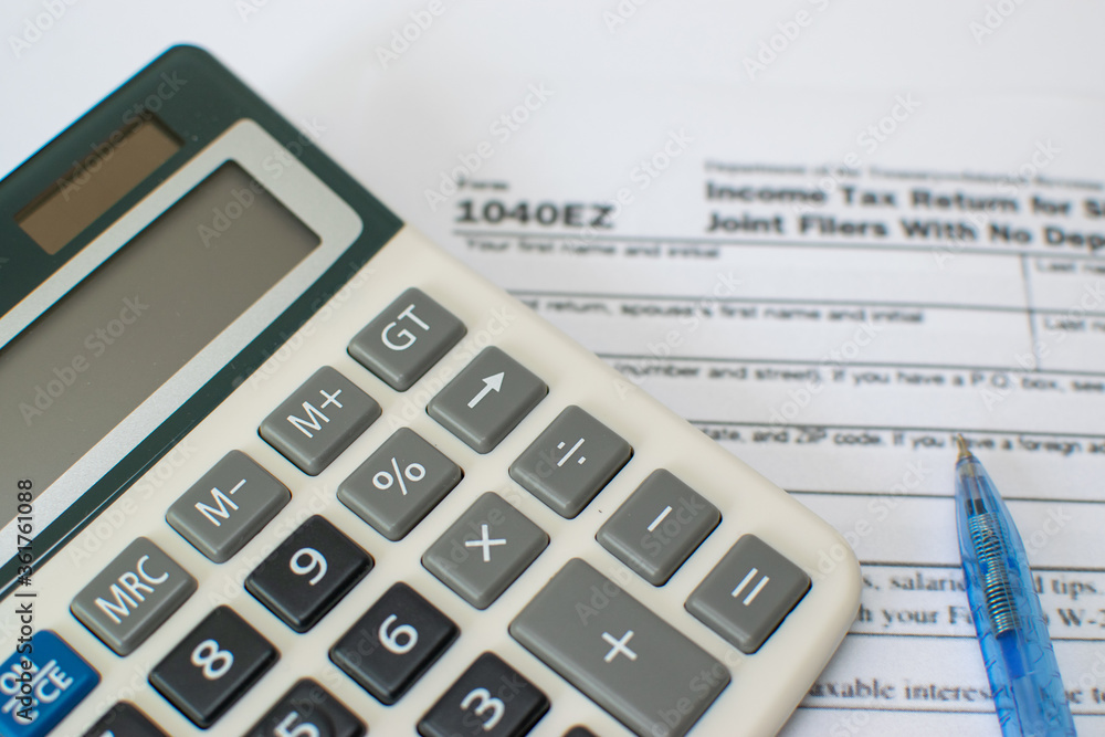 calculator and pen on financial 1040EZ tax form calculator and pen on financial 1040EZ tax form