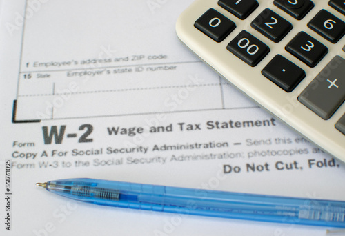 calculator and pen on financial W-2 wage and tax statement form
