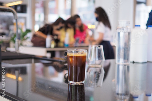 Cold Brew - A glass of iced americano coffee on wooden coaster. Selective focus.