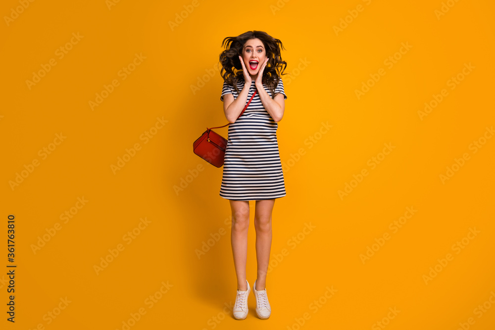 Full body photo of crazy curly lady jumping high up sunny weather day see shopping center sale prices wear white casual striped short dress clutch shoes isolated yellow color background