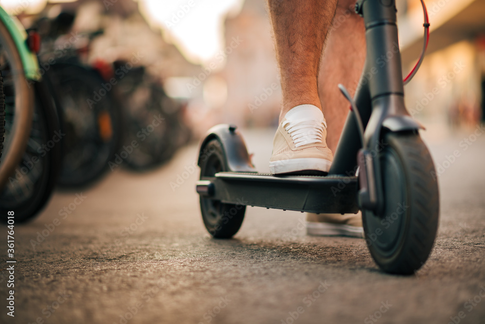 Obraz premium Eco friendly transportation concept. Man riding electric scooter, close-up.