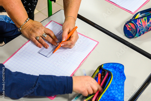 L'institutrice indique les consignes sur le cahier de l'élève. photo