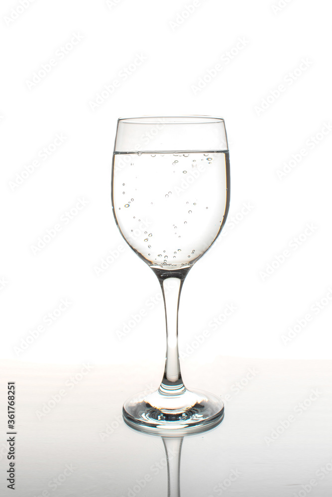 Glass of wine filled with sparkling water with reflection on a white background Glass of wine filled with sparkling water with reflection on a white background