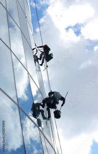Working-climbers washing the windows on high-rise building.