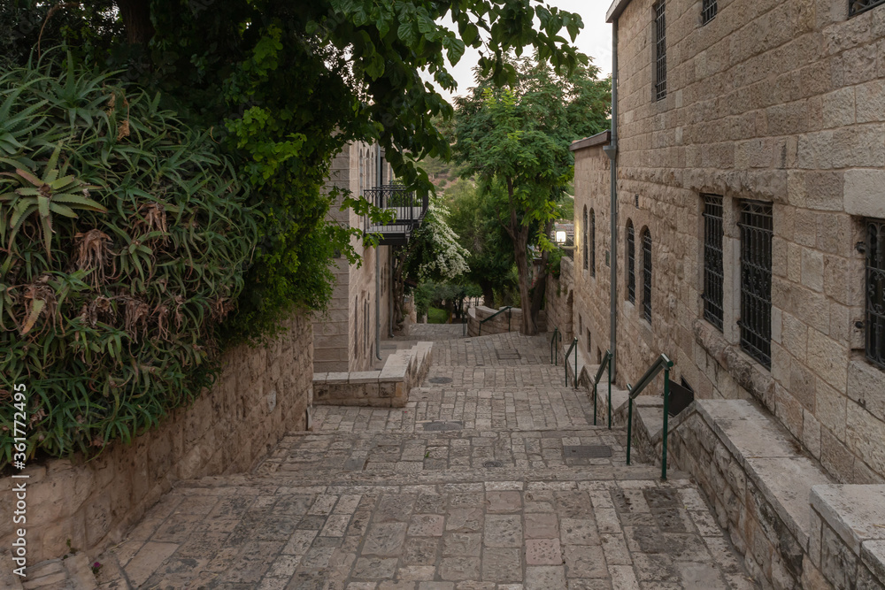 Obraz premium Residential buildings on the HaMigdal Street in the Jerusalem Mishkenot Sheananim - Hutzot Hayotzer quarter in the light of the rays of the setting sun in Jerusalem, Israel