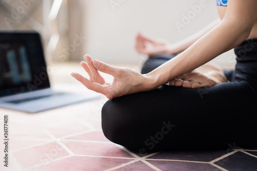female hands folded for meditation and on laptop background 