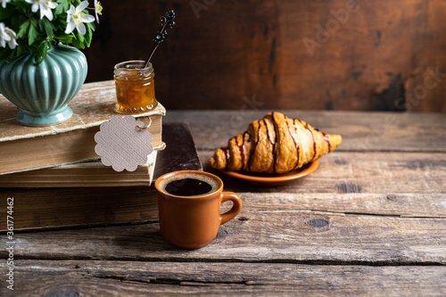 Bouquets of forest flowers, coffee cup in heart shape, old books, croissants on wooden rustic table. Good morning, breakfast, reading, cozy home, hygge concept