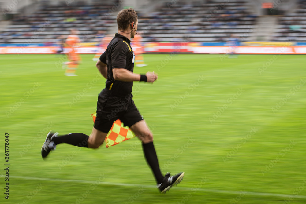Sideline referee running during football match - intentional blurry. Sideline referee running during football match - intentional blurry.