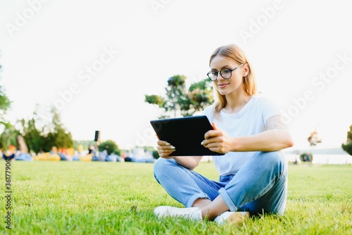 Portrait of young beautiful smiling woman with tablet pc, outdoors © Serhii