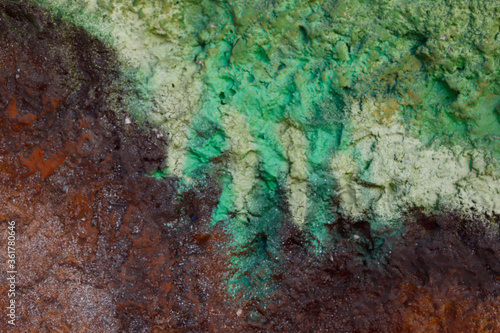 Blurred abstract background. Rough brown surface of a cement wall with green streaks of paint. Old painted wall with cracks. Horizontal, close-up, free space. Concept of construction and design.