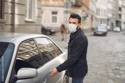 Man in a city. Person in a mask. Coronavirus theme. Man by the car. © prostooleh