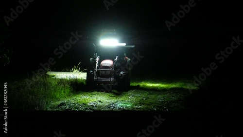A tractor cuts the grass in the night