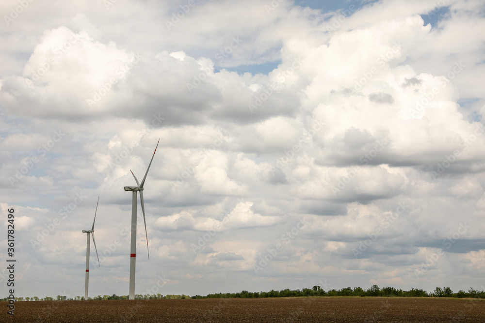 Modern wind turbines in field on cloudy day. Alternative energy source Modern wind turbines in field on cloudy day. Alternative energy source