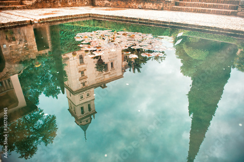 Reflection of tree and building taken from the pond at historical Alhambra Palace complex in Granada, Andalusia, Spain. Travel tourism destination