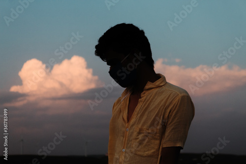 Portrait of an Indian man wearing mask standing in front of the clouds