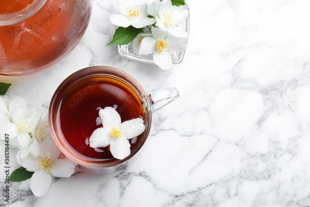 Cup of tea and fresh jasmine flowers on white marble table, flat lay. Space for text Cup of tea and fresh jasmine flowers on white marble table, flat lay. Space for text