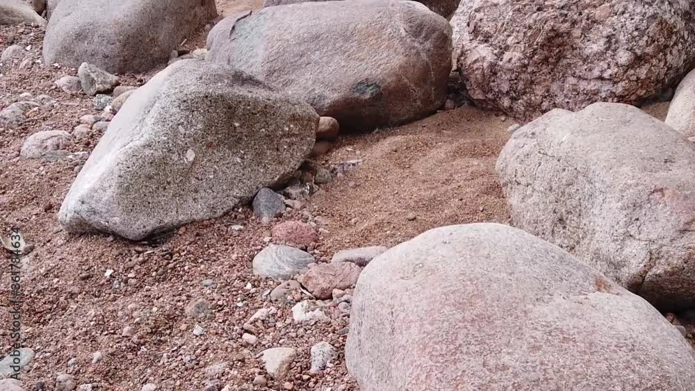 Stones and pebbles on the sand. boulders on the shore. slow motion among the rocks on the coast Stones and pebbles on the sand. boulders on the shore. slow motion among the rocks on the coast
