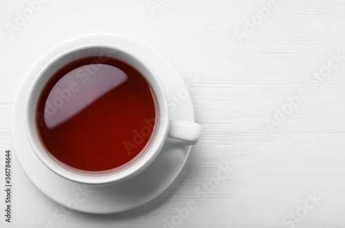 Cup of tasty black tea on white wooden table, top view. Space for text
