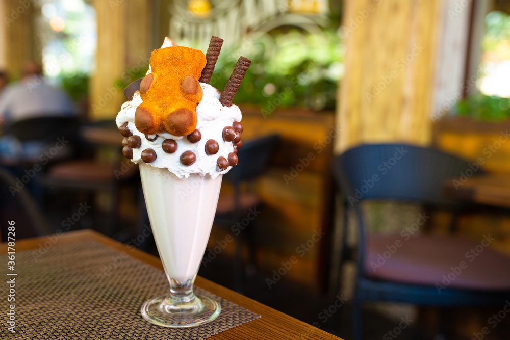 Cool milkshake with cookies and chocolate balls. Milkshake in a glass beaker on a table on a street platform in a cafe. Refreshing summer drinks Cool milkshake with cookies and chocolate balls. Milkshake in a glass beaker on a table on a street platform in a cafe. Refreshing summer drinks