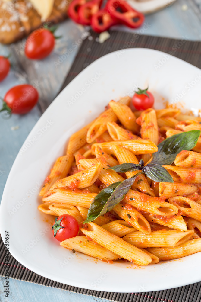 Penne pasta in tomato sauce with chicken, tomatoes decorated with parsley