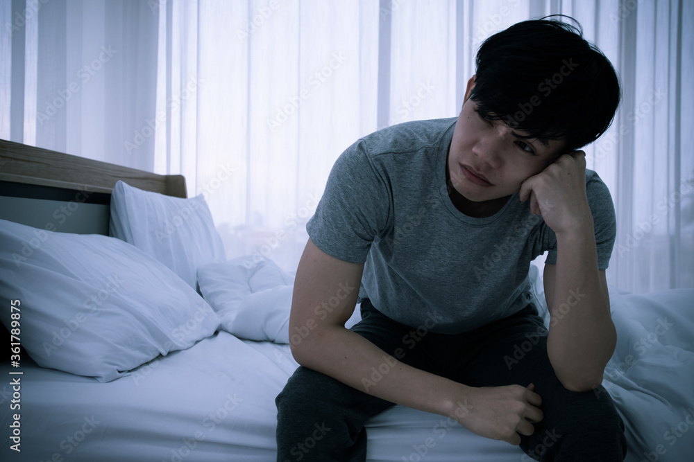 Stressed Asian young man sitting alone on bed. Bad relationship or bankrupt problem and sickness concept. Stressed Asian young man sitting alone on bed. Bad relationship or bankrupt problem and sickness concept.