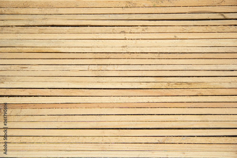 Thin wooden slats of light wood lie close to each other horizontally. View from above. Background and texture Thin wooden slats of light wood lie close to each other horizontally. View from above. Background and texture