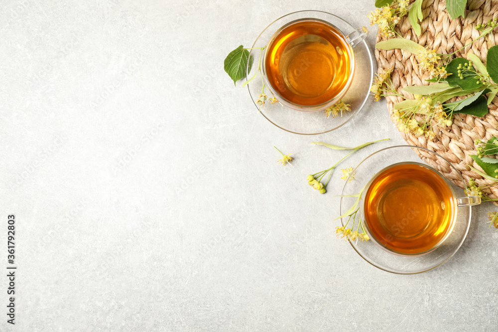 Flat lay composition with tasty tea and linden blossom on light grey table. Space for text