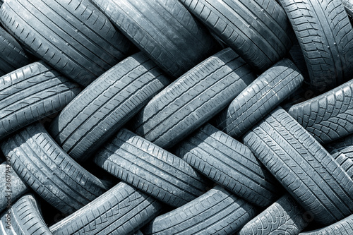 Old used weared car and truck wheels tyres pile stacked in rows stored for recycling. Heap of many rubber tires wall background. Idustrial pollution of environment photo