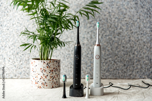 Modern rechargeable sonic or electric toothbrush set with charger in bathroom. Concept of professional oral care and healthy teeth by using ultrasonic smart toothbrush