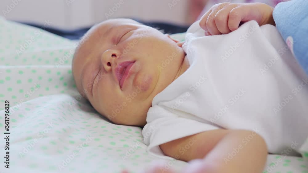 Close-up the face of a newborn baby in the early days who wakes up and opens his eyes. A newborn baby grimaces through a dream. Newborn in the first minutes of life. Close-up the face of a newborn baby in the early days who wakes up and opens his eyes. A newborn baby grimaces through a dream. Newborn in the first minutes of life.