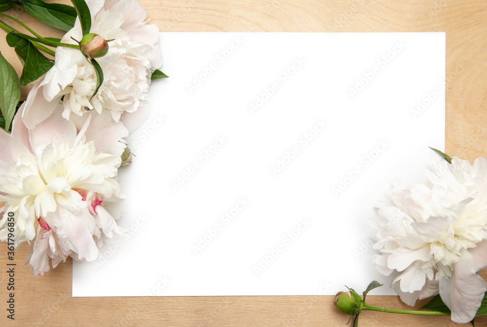 Flowers frame background. White paper card on rustic wooden background with peonies. Workspace. Blank for greetings