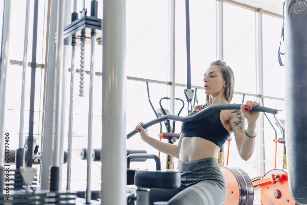 attractive athletic girl trains shoulders in simulator. view of the back muscles. healthy lifestyle. attractive athletic girl trains shoulders in simulator. view of the back muscles. healthy lifestyle.