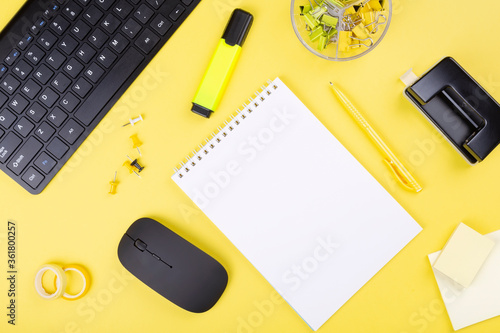 Office desk with computer and stationery, yellow background. Top view. Copy space