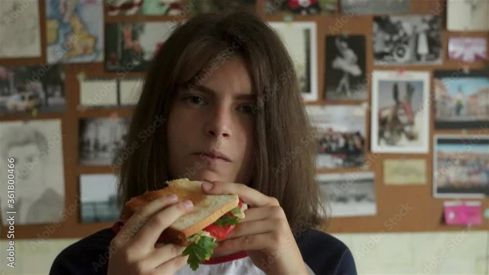 Young teenage girl staying in front of camera and eating sandwitch. having lunch, hungry students Young teenage girl staying in front of camera and eating sandwitch. having lunch, hungry students
