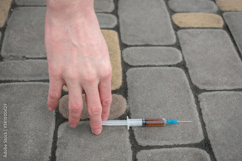 The addicts hand reaches for a syringe. The concept of addiction and drug abuse.