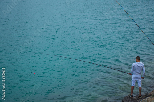 a man pulls at a fishing rod in the sea to catch fish on a rainy weekend