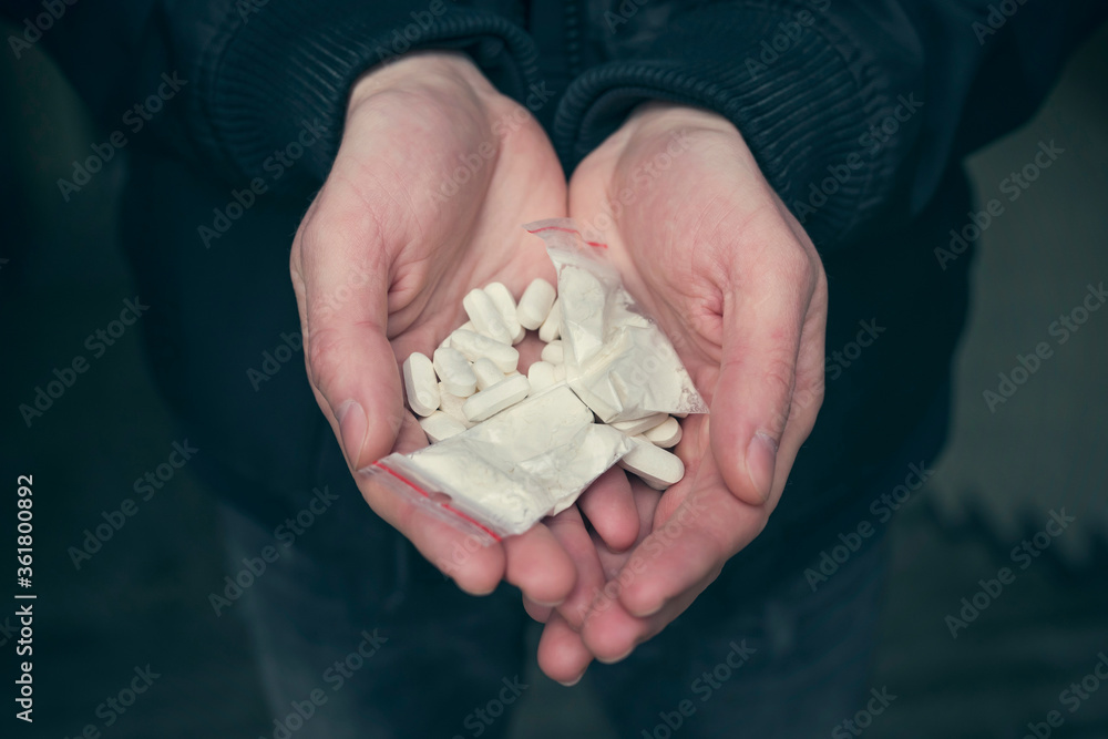 Drugs in the hands of an addict, close up. Addiction concept.