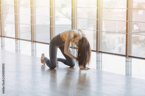 young attractive girl doing fitness exercises with yoga on the floor against the background of panoramic windows