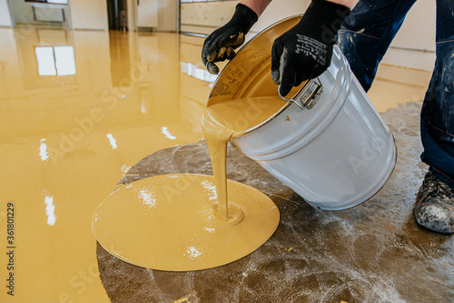 A construction worker apply epoxy resin in an industrial hall photo