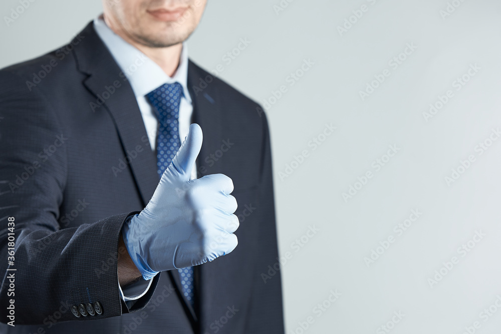 A businessman in rubber gloves gives a thumbs up. Crop photo with copy space. The concept of removing restrictions post-pandemic. A businessman in rubber gloves gives a thumbs up. Crop photo with copy space. The concept of removing restrictions post-pandemic.