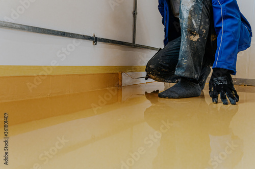A construction worker apply epoxy resin in an industrial hall