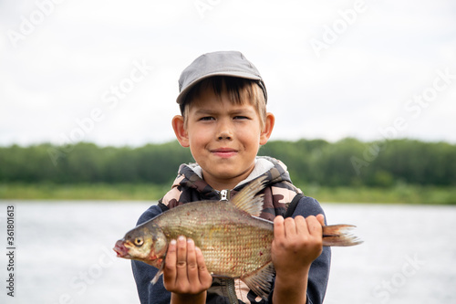 Fototapeta Naklejka Na Ścianę i Meble -  seven year old boy holds a fish he caught