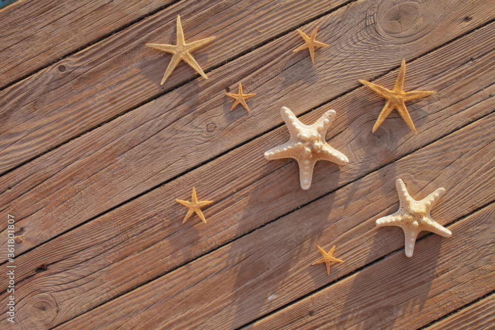 Starfish on a wooden pier poured over a wooden deck. Summer vacation concept. Holidays by the sea Starfish on a wooden pier poured over a wooden deck. Summer vacation concept. Holidays by the sea