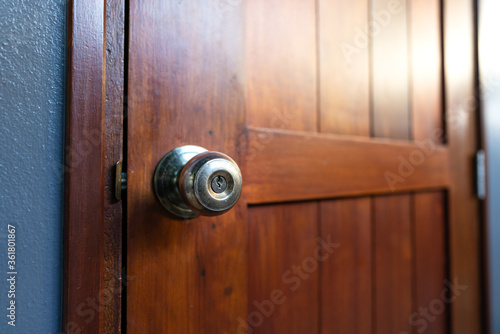 Close-up on brass metallic knob of wooden door, selected focus on the key hole. Interior house equipment object.