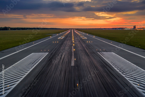 Used concrete asphalt airport empty runway with many braking marks, markings for landings and all navigation lights on. Clear for comercial airplane landing or taking off in Wroclaw airport photo