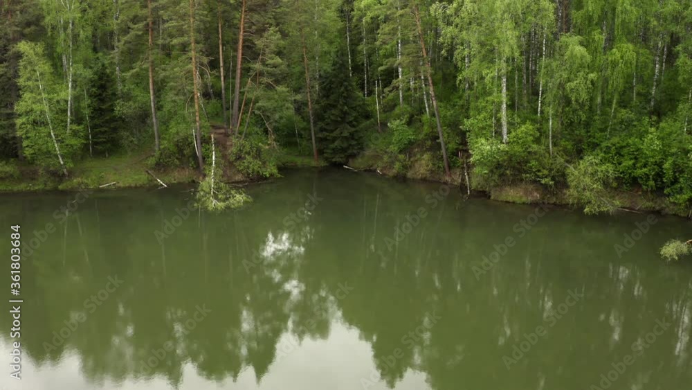 Water in a mountain forest lake with pine trees. Aerial view of lake and green forests. View on the lake between mountain forest. Over crystal clear mountain lake water. Fresh water Water in a mountain forest lake with pine trees. Aerial view of lake and green forests. View on the lake between mountain forest. Over crystal clear mountain lake water. Fresh water