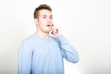 Portrait of handsome man talking on the phone and looking shocked