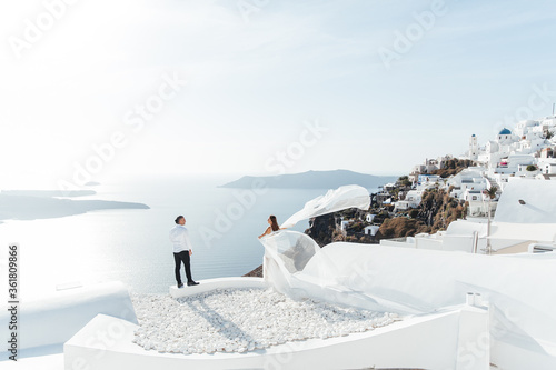 Wedding on Santorini island in Greece, beautiful couple, bride in a white wedding dress. White houses and blue sky