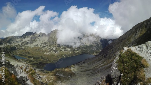 Mountains glen filled with silent crystal clear lake and calm clouds going by.